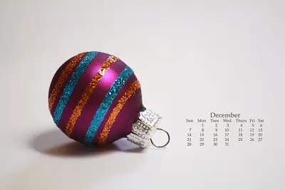 Calendario del mese di Dicembre con una pallina di Natale viola su sfondo chiaro