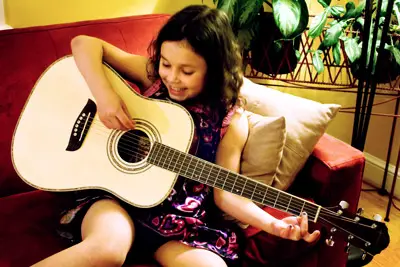 Una bambina concentrata impara a suonare la chitarra